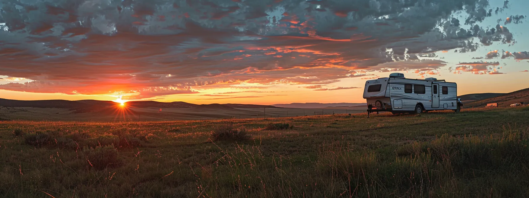 a vibrant sunset casts a warm glow over a mobile home trailer being expertly navigated through an expansive, open landscape, highlighting the intricate details of both the trailer and the surrounding nature.